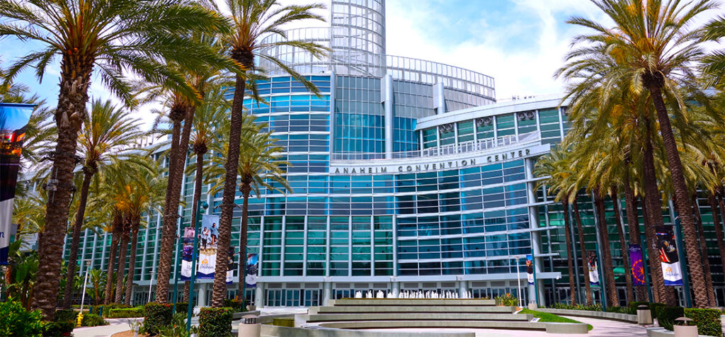 Front entrance of the Anaheim Convention Center with glass facade and palm trees.