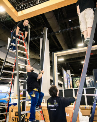 Team lifting structural beam into place for booth assembly.