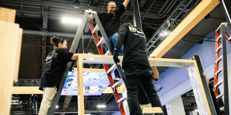 Installer fastening overhead booth structure.