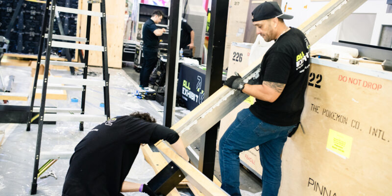 Installers preparing and securing booth framework panels.