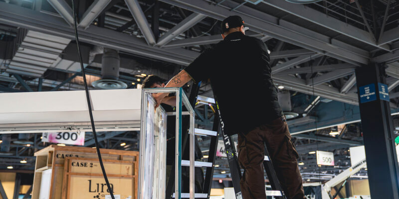 Installer measuring and aligning booth structure components.