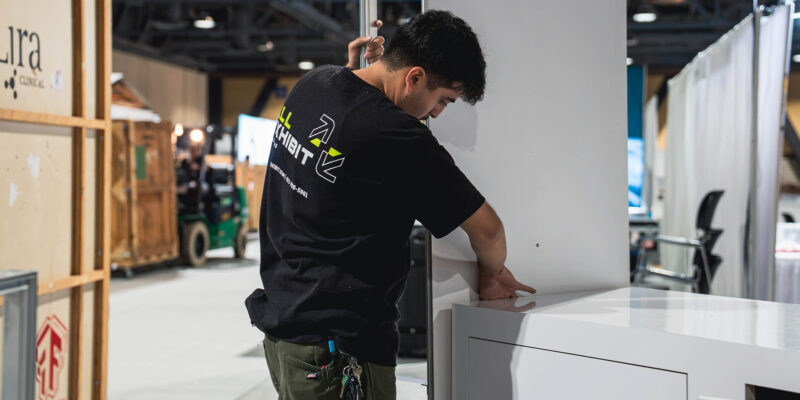 Crew member adjusting booth panels on the trade show floor.