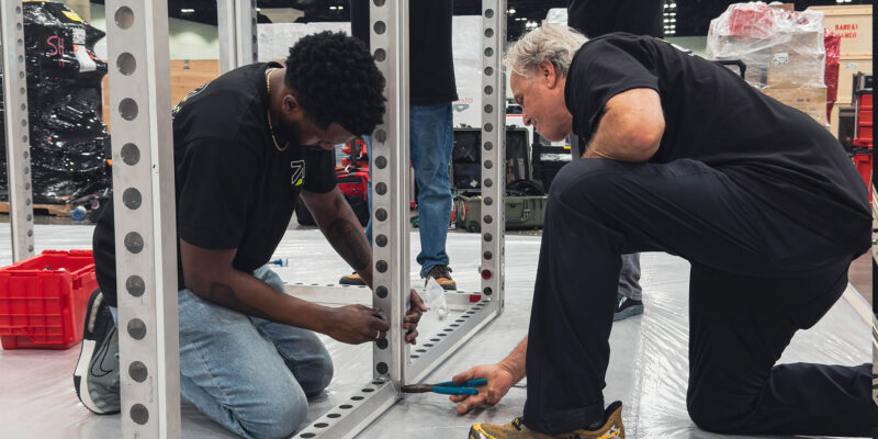 Crew members securing booth components on trade show floor.