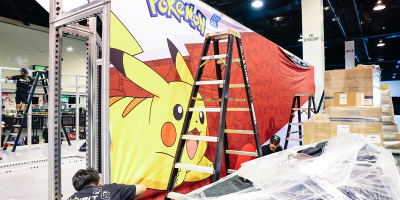 Large trade show booth wall with bold Pokemon red and yellow graphics.
