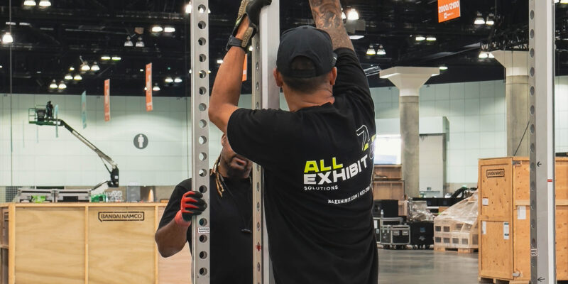 Installer lifting booth structure beam during setup.