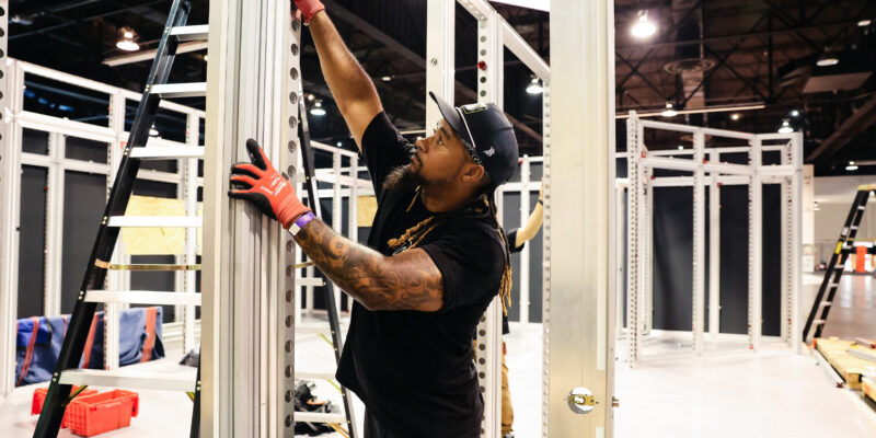 Crew member fastening booth frame during build.