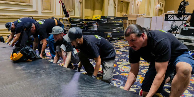 Team members lifting and positioning trade show booth flooring panels.