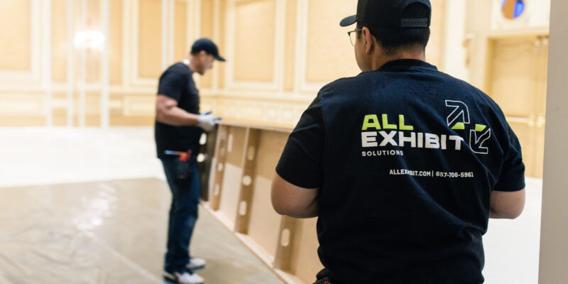 All Exhibit Solutions crew preparing booth flooring during installation.